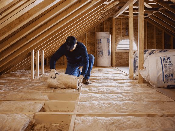 A contractor installing insulation in an attic.