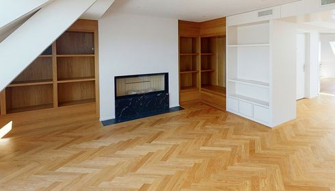 Spacious room with herringbone wood flooring and built‑in shelves