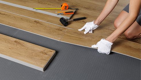 Person installing laminate flooring with tools