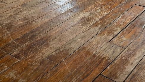 Close-up of worn hardwood floor with scratches and dents