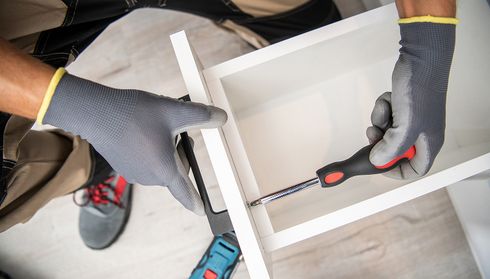 Close-up of worker installing cabinet hardware with screwdriver