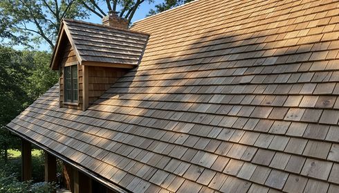 Sunlit cedar shingle roof with a dormer window