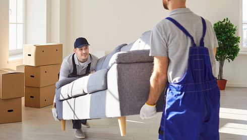 Movers carrying a sofa in a living room