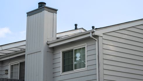 Gray siding on a house exterior with a chimney