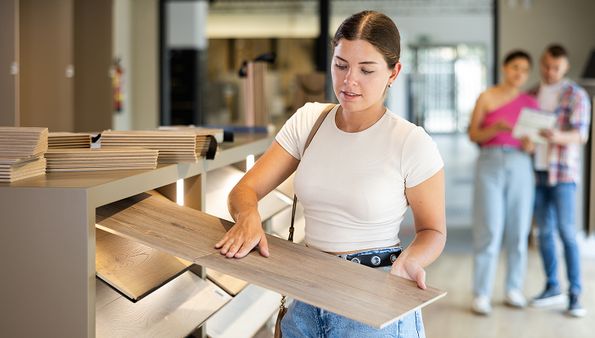 Person selecting a hardwood floor plank in a showroom