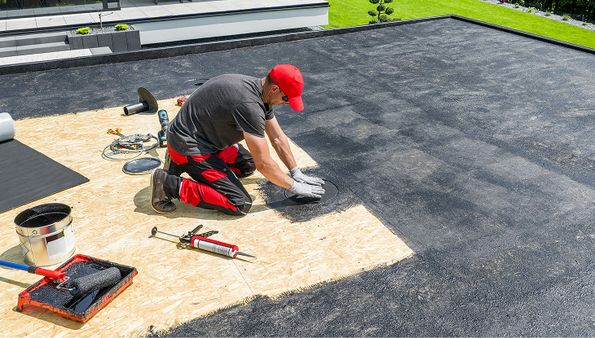 Contractor installing membrane material on a flat roof